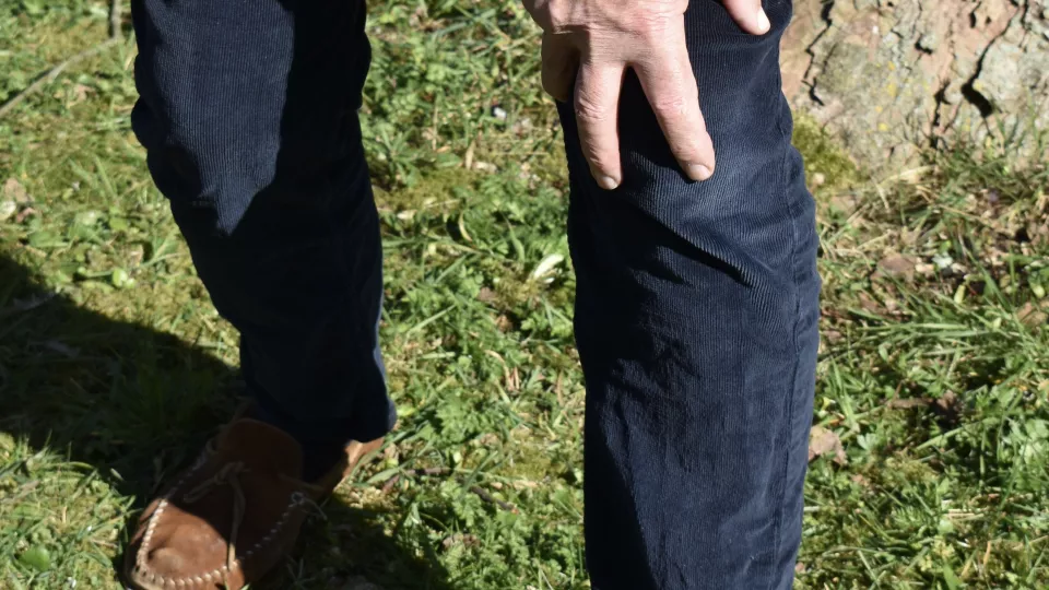 Person in jeans with two hands on one knee.