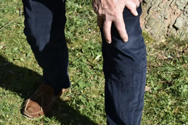 Person in jeans with two hands on one knee.