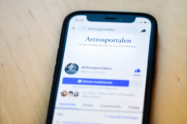 A photo of a mobile phone with the Swedish Arthritis Portal Facebook page showing.