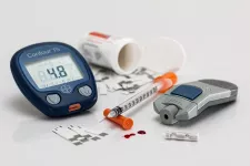 Photo of a blood glucose meter, a lancing device, an open box of pills, a syringe and 