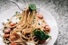 A plate with pasta, basil and tomatoes. 