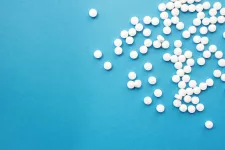 Many white small pills laying on a blue background.