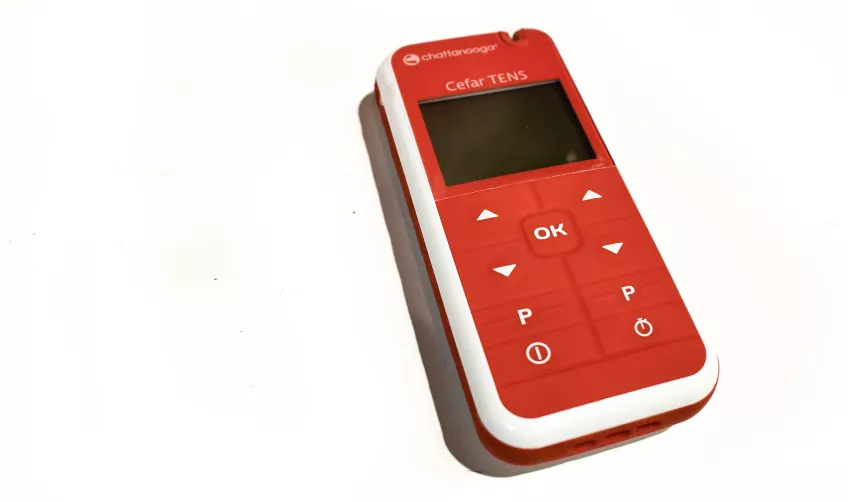 Photo of a red and white TENS machine on a white background.