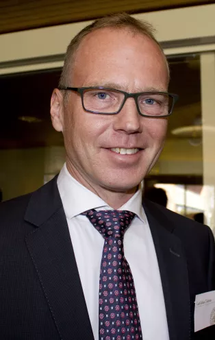 A portrait photo of Carl Johan Tiderius. He is a white male with glasses wearing a suit and a patterned tie.